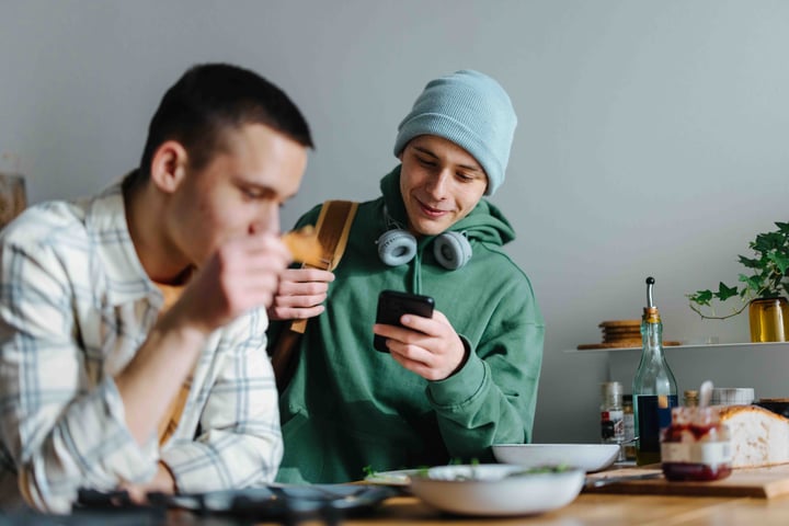 two peope eating breakfast checking phone