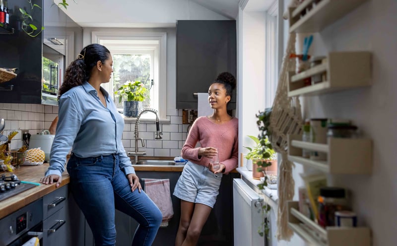 Adult talking to teenager in the kitchen