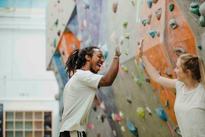 two people giving high five at bouldering gym