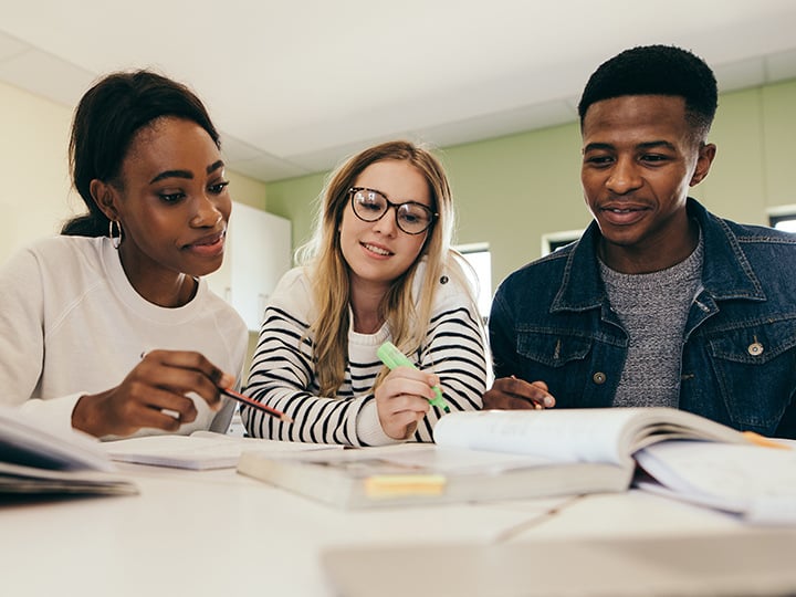 Three students looking through a book