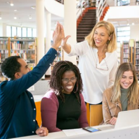 Fours students smiling around a computer