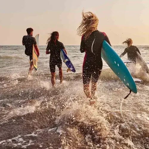 Surfers running into ocean with their surfboards